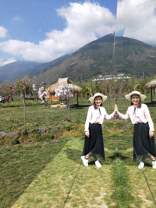 Two women in a field with a mountain in the backgroundDescription automatically generated